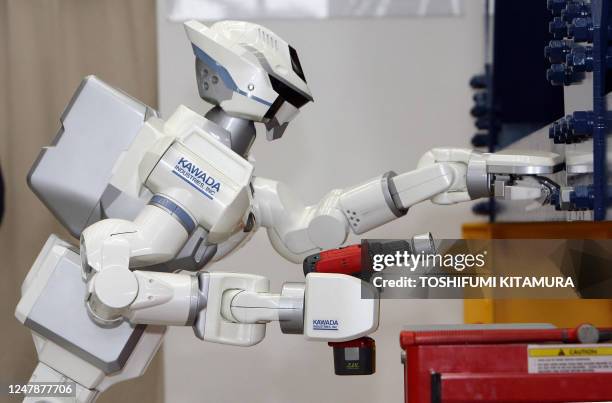 The HRP-3 Promet Mk-II humanoid robot balances its body while screwing a nut by an electronic impact wrench during its press preview at Kawada...