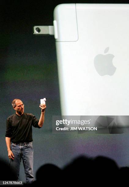 Apple CEO Steve Jobs shows off his new wireless adpator during Apple's announcement of the release of Apple 'iTunes' Music Store in the UK, France...