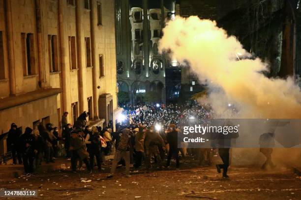 Protesters clash with riot police near the Georgian parliament in Tbilisi on March 7, 2023. - Georgian police used tear gas and water cannon against...