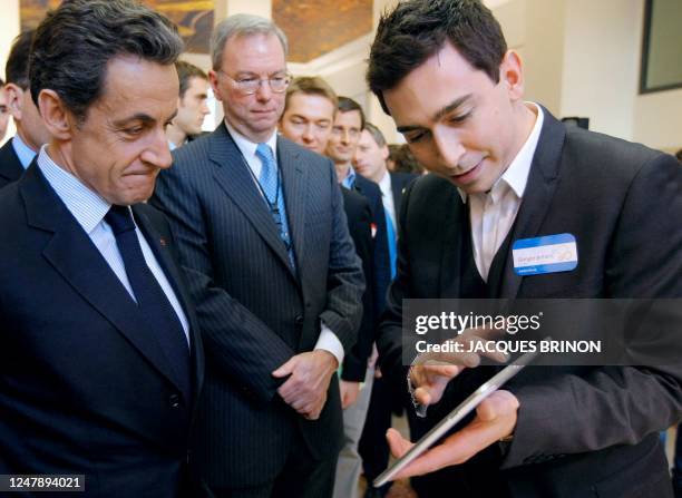 French President Nicolas Sarkozy listens to Google employee Robbie Dowek demonstrating a tablet as Google executive chairman Eric Schmidt looks on...