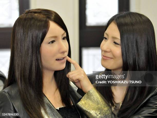 Model pokes the face of a humanoid robot called "Geminoid-F" shaped to resemble the model at a press conference in Osaka, on April 3, 2010....