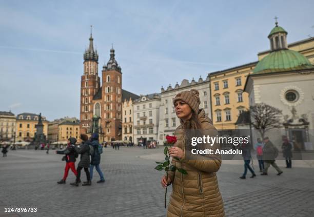 Sylwia Pieczara, a journalist at TVP Krakow, walks through the Main Market Square in Krakow holding a red rose on the eve of International Women's...
