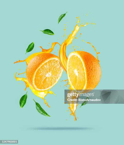 juice splashes out from sliced orange - citrus splash stock pictures, royalty-free photos & images