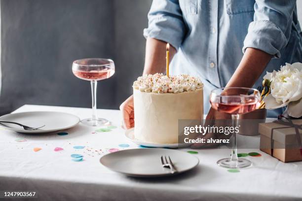 woman setting up table for birthday celebration - holding birthday cake stock pictures, royalty-free photos & images