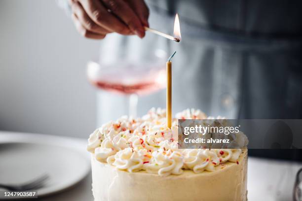 mujer mano encendiendo vela de cumpleaños - vela de cumpleaños fotografías e imágenes de stock