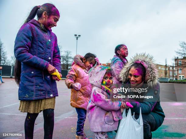 Woman shows her little girl how to use a fake gun to throw colored powder during the Holi festival in The Hague. Millions of people around the world...