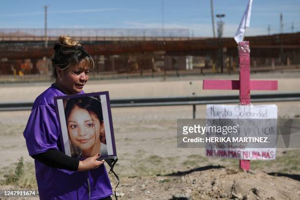 Susana Montes shows a photo of her daughter Maria Guadalupe Perez Montes, a victim of disappearance, trafficking, and femicide, next to a pink cross...