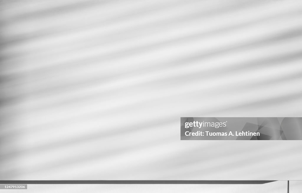 Play of light and shadows, diagonal delicated striped shadows on a white wall.