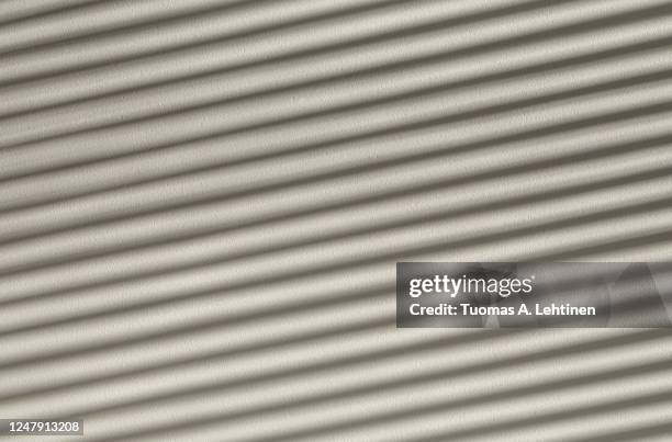 play of light and shadows, diagonal striped shadows on a white stone wall. - window blinds stock pictures, royalty-free photos & images