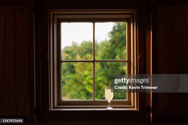 glass of lemonade sitting on window sill with view of trees - window frame stock pictures, royalty-free photos & images