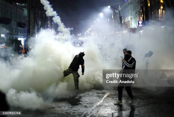 Protestor throws back a canister with tear gas during a protest against bill on foreign influence transparency in Tbilisi, Georgia on March 8, 2023.