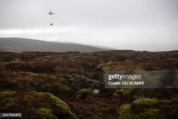 Photograph taken on February 27, 2023 shows a stone dam created by rural conservation specialists to aid peatland restoration in Cumbria near the...