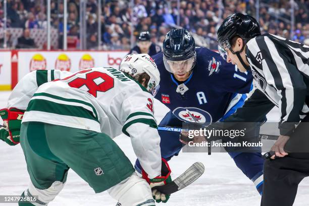 Ryan Hartman of the Minnesota Wild and Adam Lowry of the Winnipeg Jets get set for a second period face-off at the Canada Life Centre on March 8,...