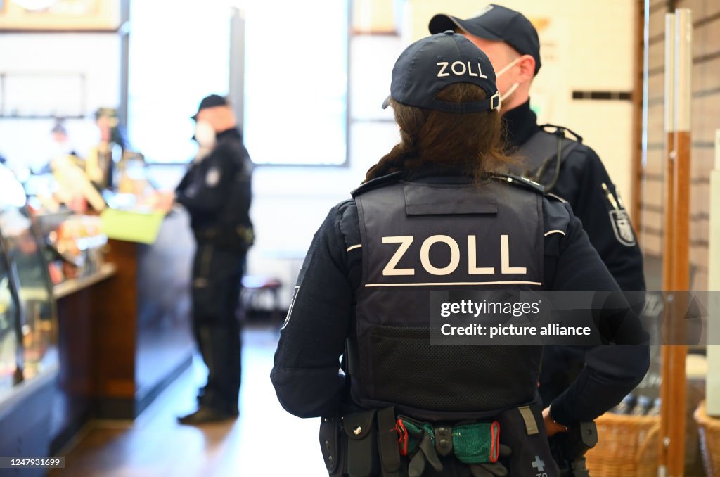 Customs officers check employees at a café. Several hundred officers ...