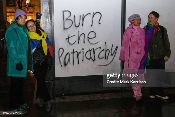 Protesters pose alongside graffiti in Trafalgar Square reading 'Burn the Patriarchy' during an International Women's Strike event to mark...