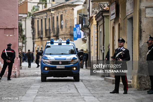 Police car drives down a street where Carabinieri policemen stand guard near the town hall of Cutro, Calabria region, on March 9, 2023 within a...