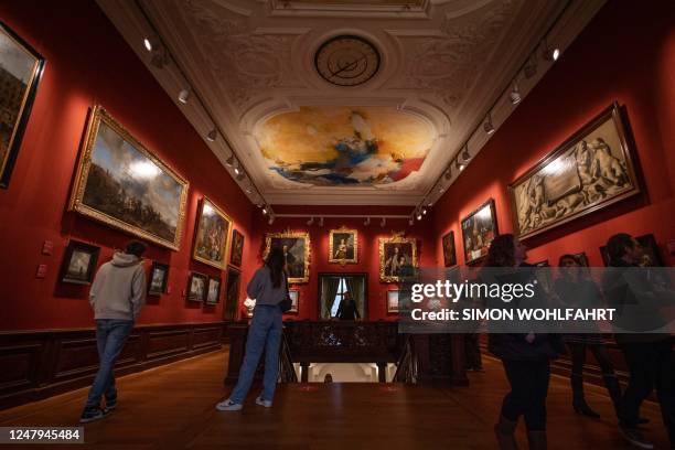 Visitors look at paintings in the Mauritshuis museum in The Hague on March 9, 2023. / RESTRICTED TO EDITORIAL USE - MANDATORY MENTION OF THE ARTIST...