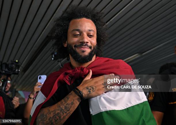 Brazilian defender Marcelo, wrapped in a flag of Brazilian team Fluminense, arrives at Galeao Airport in Rio de Janeiro, Brazil, on March 9 on the...