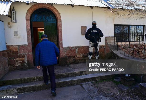 Man enters the office of the San Francisco Javier Parish, guarded by a National Guard officer, in Cerocahui, in the Tarahumara mountains of the state...