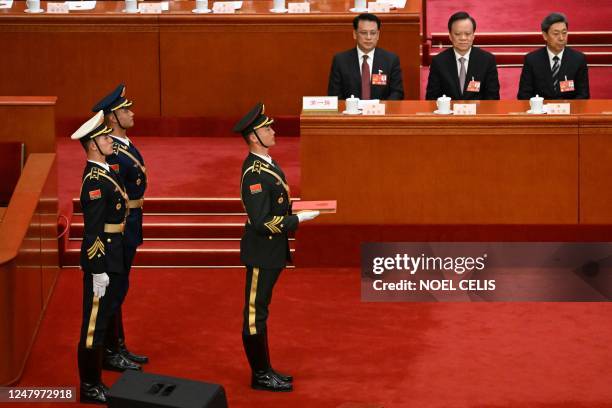 People's Liberation Army soldiers carry a copy of China's constitution as they prepare for China's President Xi Jinping to swear an oath after being...