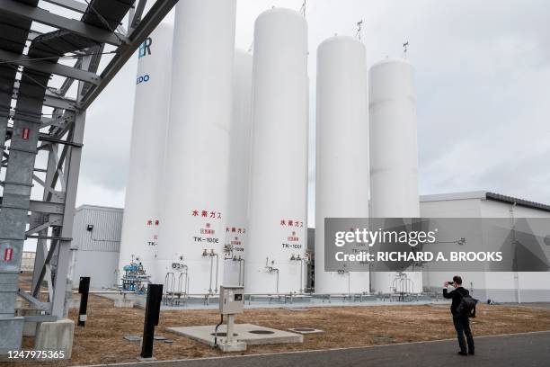 This photo taken on February 15, 2023 shows a visitor taking a photo of some of the hydrogen storage and supply facilities at the "Fukushima Hydrogen...