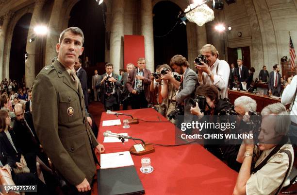 News photographers crowd around the witness table 07 July 1987 in Washington, D.C to take pictures of Lieutenant-Colonel Oliver North , former aide...