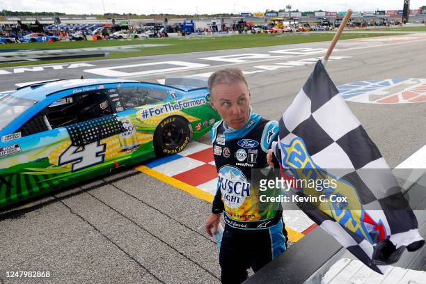 Kevin Harvick, driver of the Busch Light For The Farmers Ford, takes the checkered flag to celebrate winning the NASCAR Cup Series Folds of Honor...