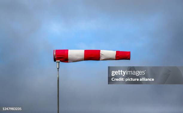 March 2023, Baden-Württemberg, Riedlingen: A gap in the clouds has formed behind a windsock standing in the storm. Photo: Thomas Warnack/dpa