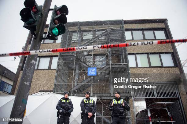 Police officers stand outside a building where a shooting the night before left at least eight people dead and eight more wounded in Alsterdorf...