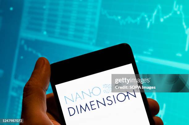 In this photo illustration, the 3D printing company Nano Dimension logo is seen displayed on a smartphone with an economic stock exchange index graph...