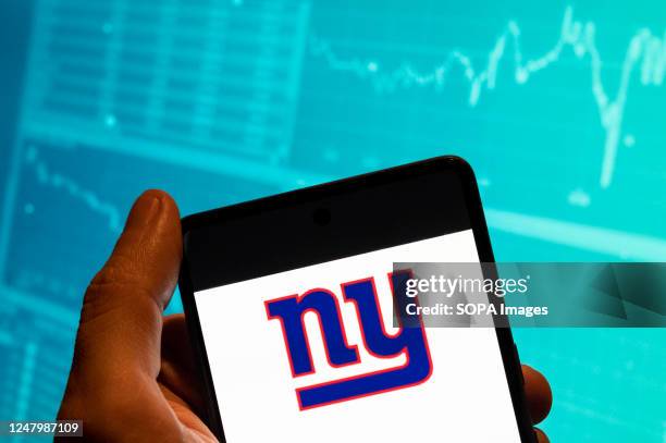 In this photo illustration, the American professional football NFL team the New York Giants logo is seen displayed on a smartphone with an economic...