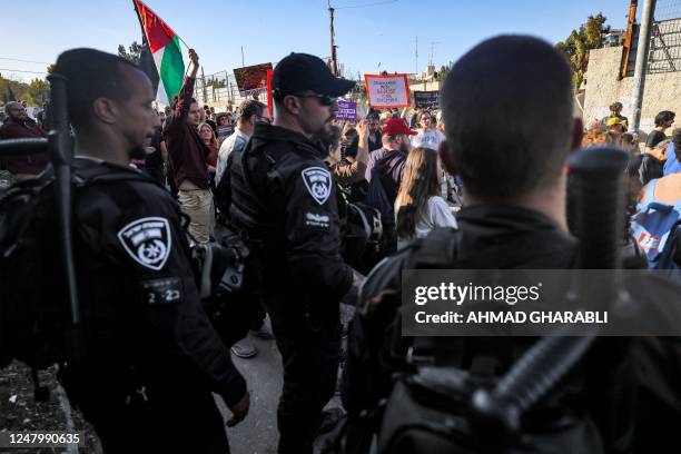 Israeli policemen look on as left-wing Israeli peace activists and Palestinians march past with Palestinian national flags during a demonstration...