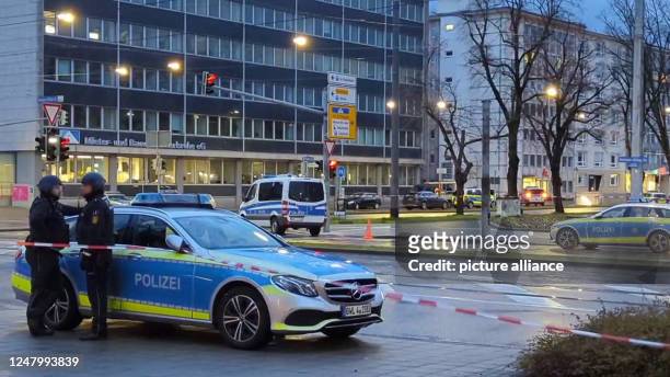 March 2023, Baden-Württemberg, Karlsruhe: Police officers stand by a police vehicle in Karlsruhe. One or more hostages had been taken in a pharmacy,...