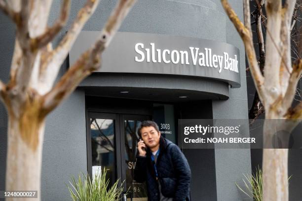 Pedestrian speaks on a mobile telephone as he walks past Silicon Valley Banks headquarters in Santa Clara, California on March 10, 2023. - US...