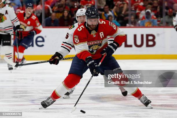 Aaron Ekblad of the Florida Panthers skates with the puck against Joey Anderson of the Chicago Blackhawks at the FLA Live Arena on March 10, 2023 in...