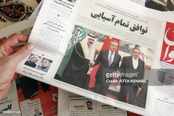 Man in Tehran holds a local newspaper reporting on its front page the China-brokered deal between Iran and Saudi Arabia to restore ties, signed in...