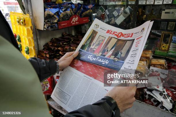 Woman in Tehran holds a local newspaper reporting on its front page the China-brokered deal between Iran and Saudi Arabia to restore ties, signed in...