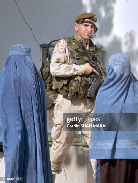 Macedonian soldier of the International Security Assistance Force walks past two burqa-clad Afghan women during a patrol in the streets of Kabul, 05...