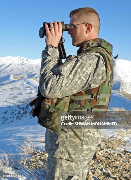 Soldier looks through his binoculars as he stands on top of Shinori Mountains in northern Iraq near Iranian border 18 February 2006 as search...