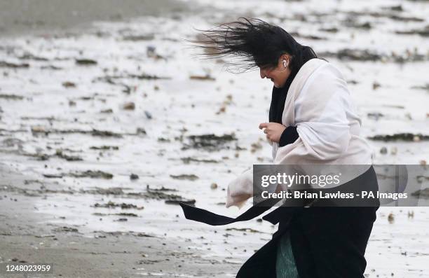 Woman struggles against the elements on Dollymount strand on a wet and windy day in Dublin. Picture date: Saturday March 11, 2023.