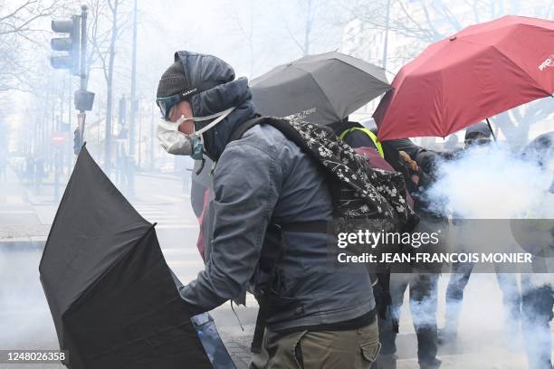 Protestors hold umbrellas in a cloud of tear gas during a demonstration, as part of a nationwide day of strikes and protests called by unions over...