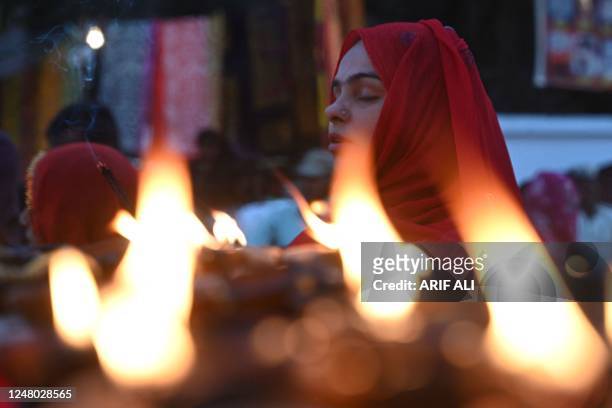 Devotee offers prayer at the shrine of Muslim Sufi saint Shah Hussain on the occasion of festival "Mela Chiraghan" in Lahore on March 11, 2023.