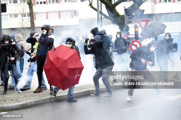 Protestors hold umbrellas in a cloud of tear gas during a demonstration, as part of a nationwide day of strikes and protests called by unions over...