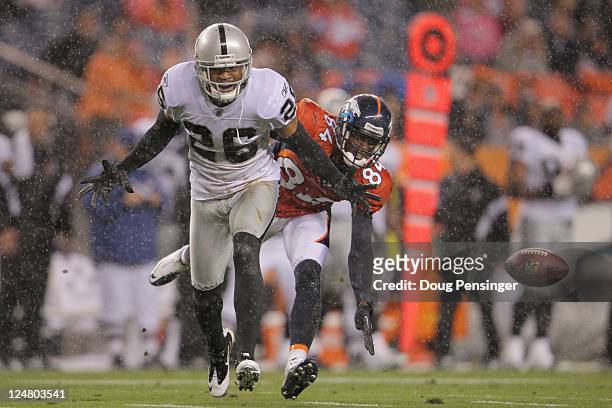 Wide receiver Brandon Lloyd of the Denver Broncos and cornerback Stanford Routt of the Oakland Raiders vie for the ball in the rain at Sports...