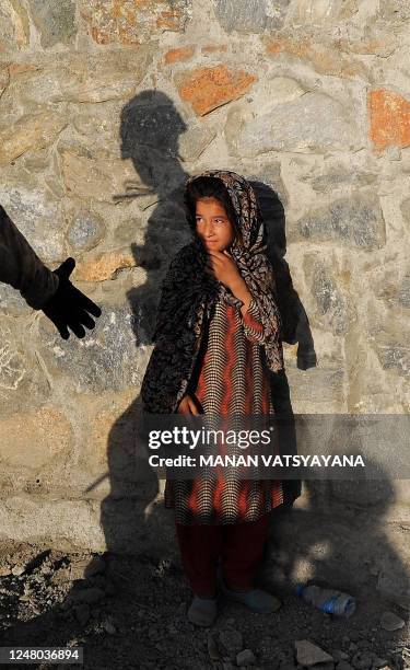 Young Afghan girl looks up shyly as a US soldier from the 2nd Platoon Alpha 3-71 Cavalry offers to shake hands during a patrol mission in the Baraki...