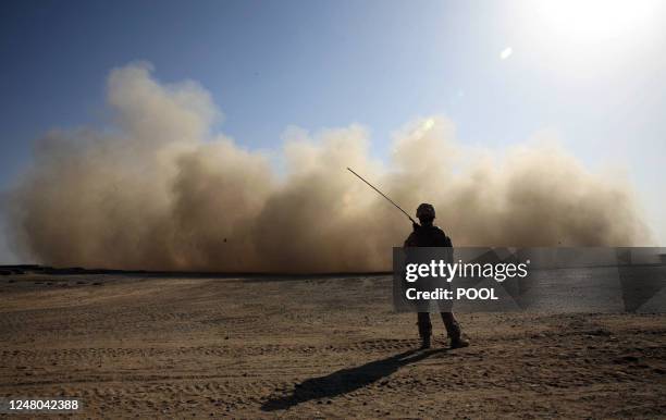 Marine stands guard as a landing helicopter churns up a cloud of dust in Marjah in Afghanistan's Helmand province on February 18, 2010. About 15,000...