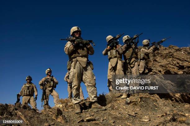 Marines from Fox Company 2nd Battalion 3rd Marines point their weapons on top of a mountain after clearing through caves suspected of being used by...