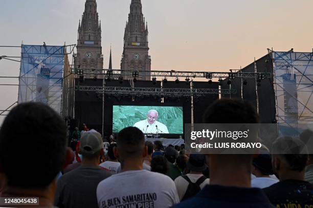 Faithfuls watch a video as they attend a mass in front of the Basilica of Lujan on March 11 in Lujan, Buenos Aires province, Argentina, to celebrate...