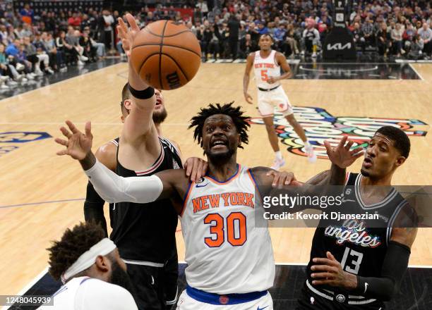 Julius Randle of the New York Knicks is held down by Ivica Zubac and Paul George of the Los Angeles Clippers during the first half during the second...