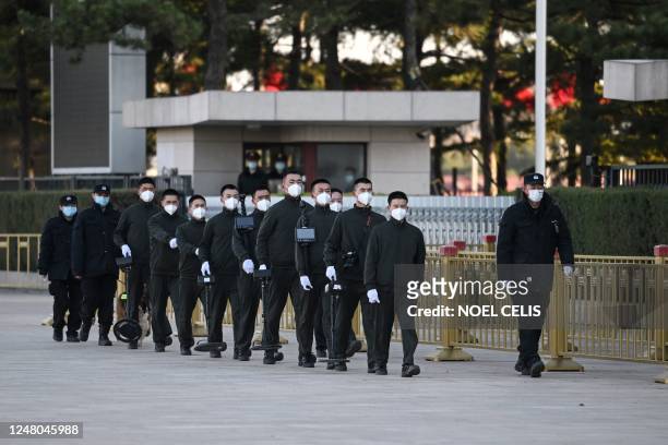 Security officers walk outside the Great Hall of the People ahead of the fifth plenary session of the National People's Congress in Beijing on March...